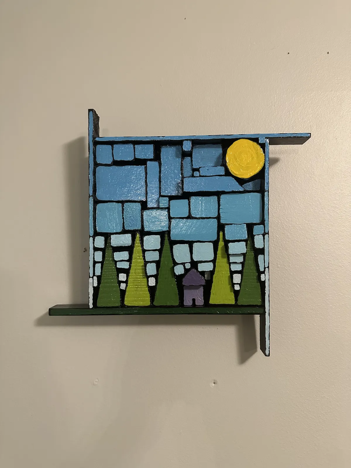 Finished wall piece of a purple cabin among green trees under a blue sky