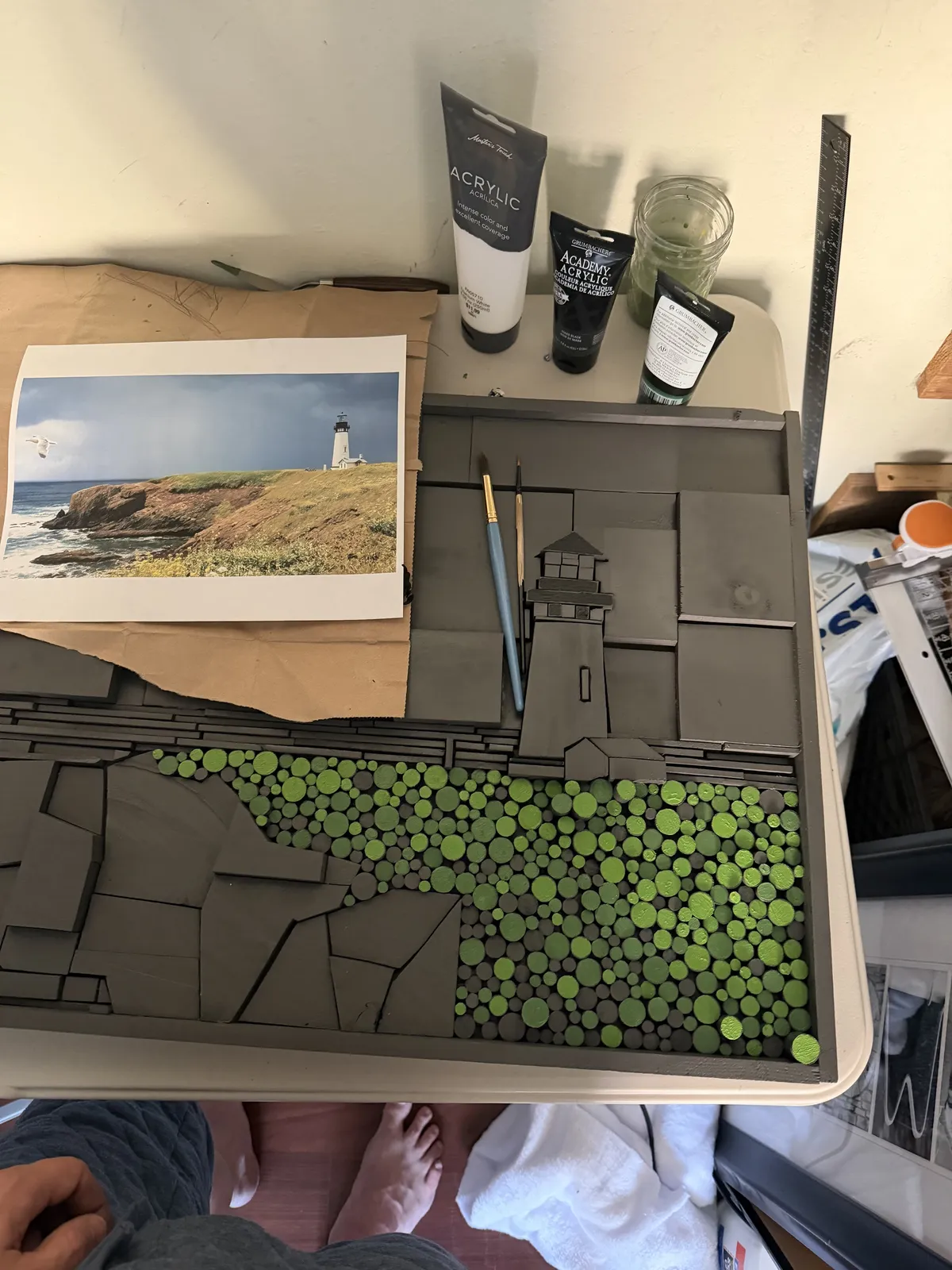 The lighthouse piece being painted beside the reference photo