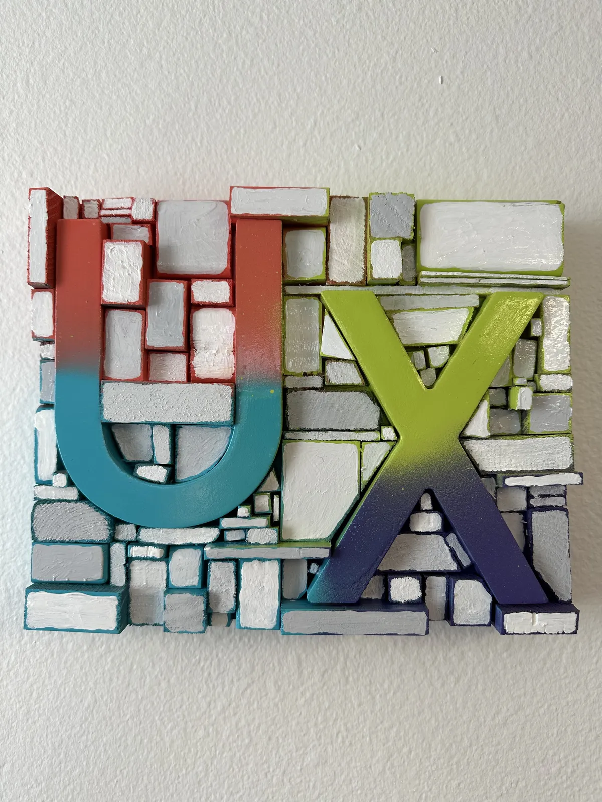 Finished UX sign painted in a red, teal, green and purple gradient